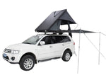 Load image into Gallery viewer, DesertX Trailblazer black two-person hard shell rooftop tent with attached awning on a white SUV.