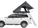 Load image into Gallery viewer, DesertX Trailblazer dark grey two-person hard shell rooftop tent mounted on a white SUV with an extended ladder.
