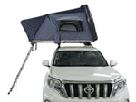 Load image into Gallery viewer, DesertX Basecamp dark grey hardshell rooftop tent mounted on a white SUV, with an extended ladder.