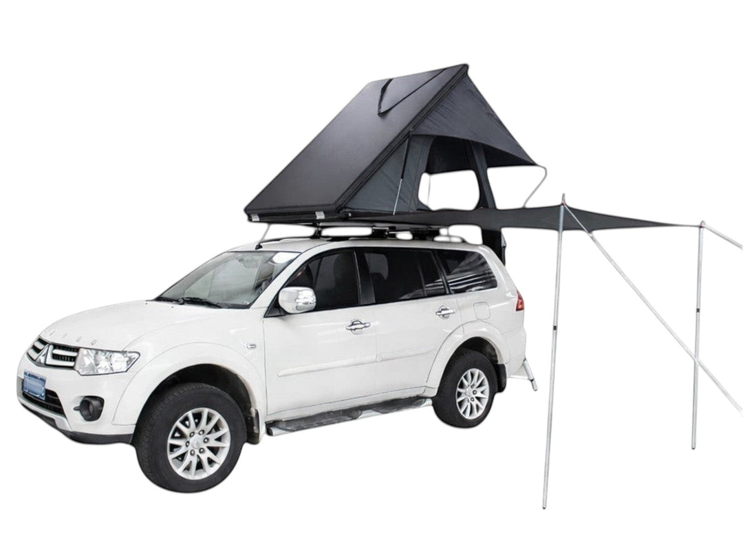 DesertX Trailblazer black two-person hard shell rooftop tent with attached awning on a white SUV.