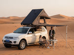 Load image into Gallery viewer, DesertX Trailblazer two-person hard shell rooftop tent mounted on a white SUV, with an attached awning.